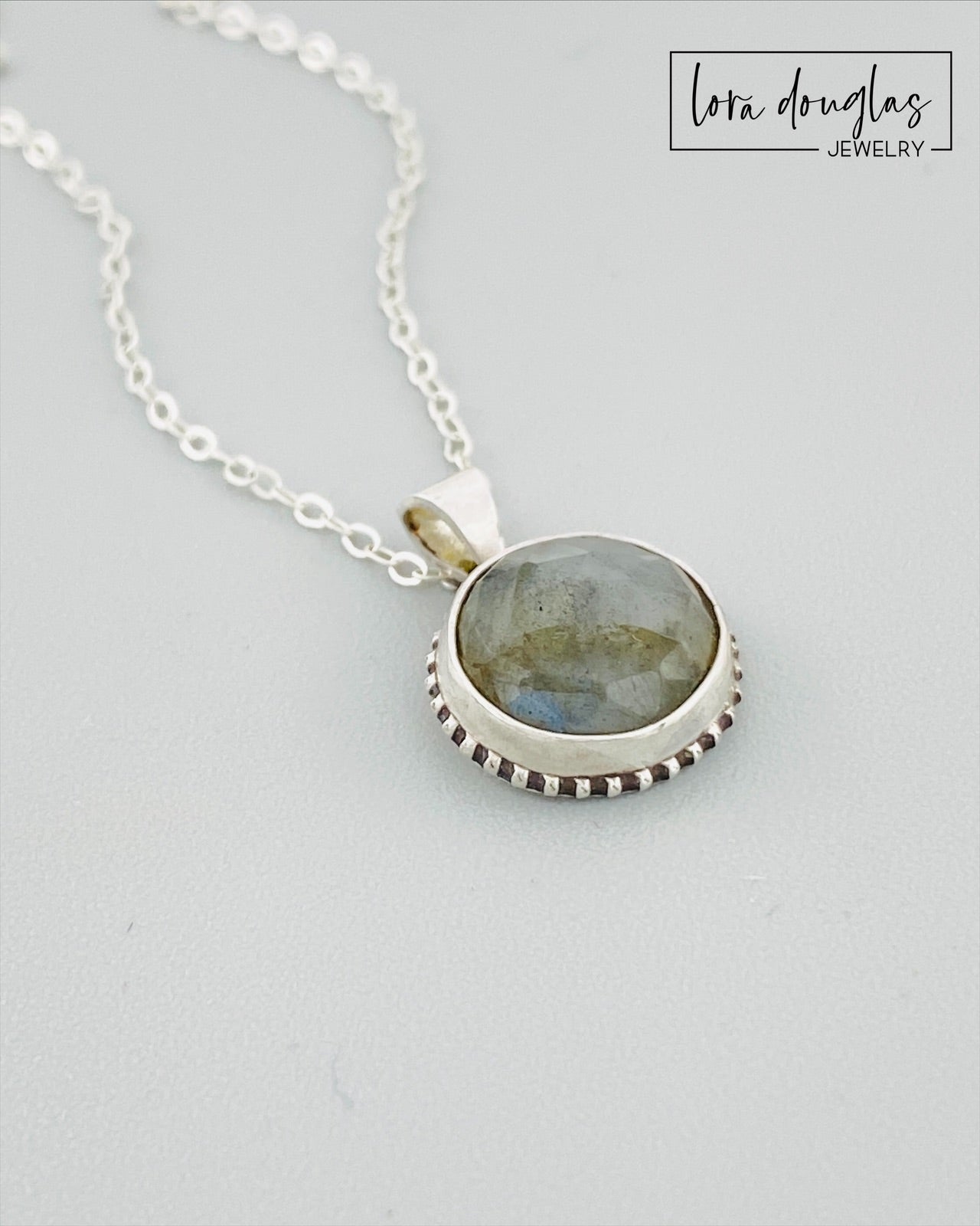 A sterling silver pendant necklace with a faceted labradorite gemstone in the center, attached to an 18-inch chain with a C clasp.