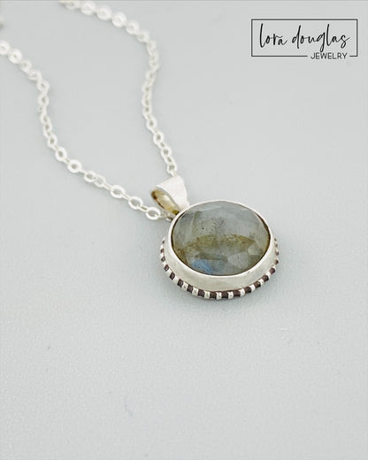 A sterling silver pendant necklace with a faceted labradorite gemstone in the center, attached to an 18-inch chain with a C clasp.