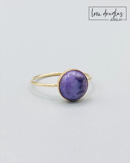 Gold-filled ring with a purple charoite stone set in a gold-filled band, displayed against a white background.