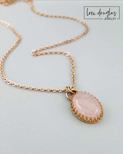 A bronze necklace with a rose quartz pendant, featuring a lobster clasp.