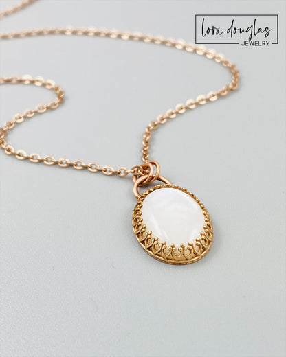 A bronze necklace with a stainless steel chain featuring a round moonstone pendant in a bronze setting.
