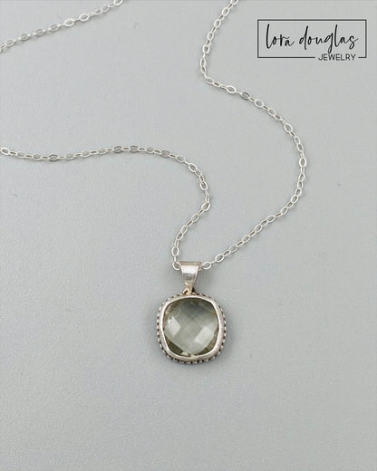 A sterling silver pendant necklace with a faceted green amethyst gemstone, attached to a silver chain.