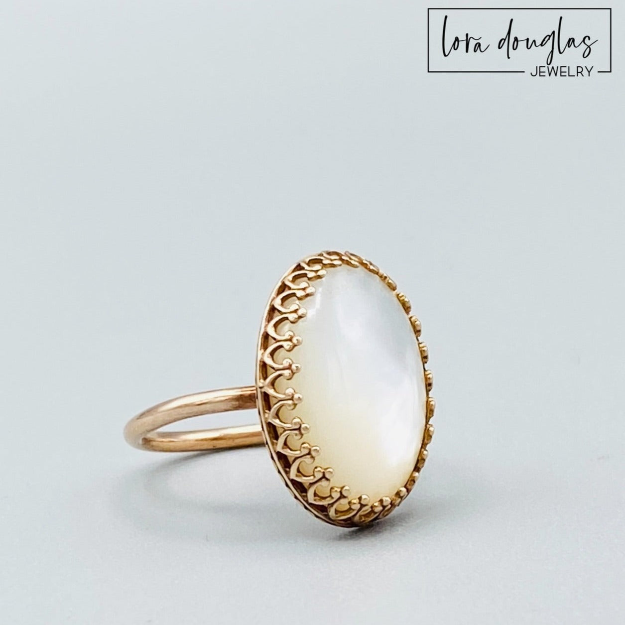 A bronze ring with a mother of pearl stone set in a gold-colored setting.