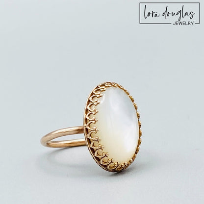 A bronze ring with a mother of pearl stone set in a gold-colored setting.