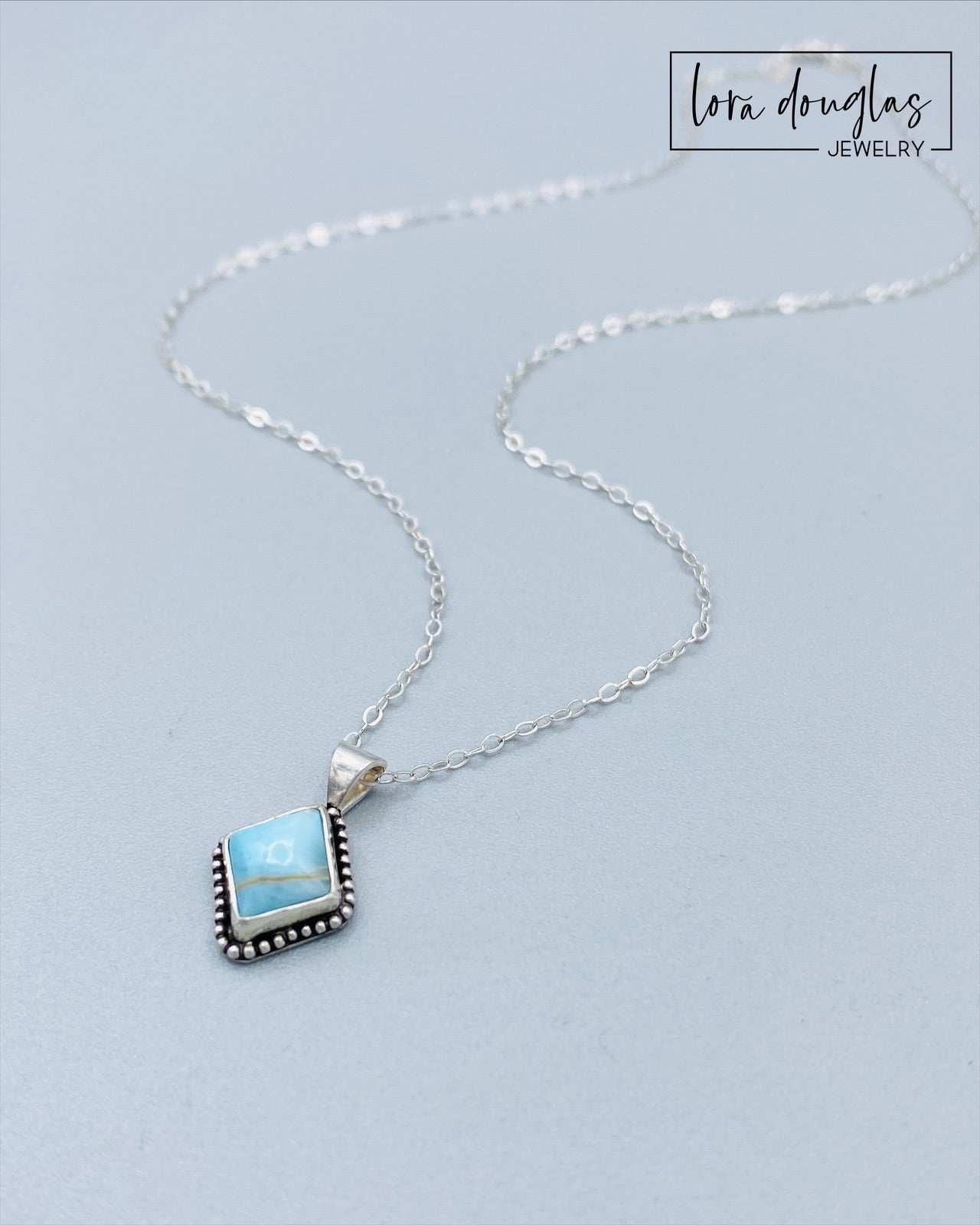A sterling silver pendant necklace with a turquoise stone and a silver chain.