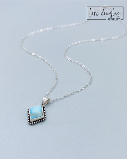 A sterling silver pendant necklace with a turquoise stone and a silver chain.