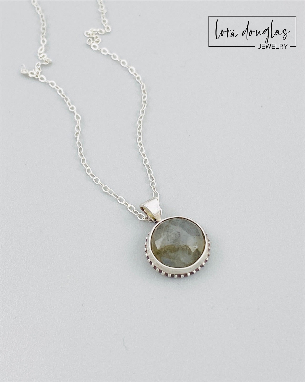A sterling silver pendant necklace with a faceted labradorite gemstone in the center, attached to an 18-inch chain with a C clasp.