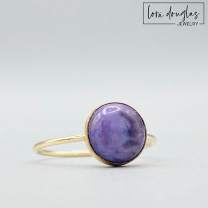 Gold-filled ring with a purple charoite stone set in a gold-filled band, displayed against a white background.