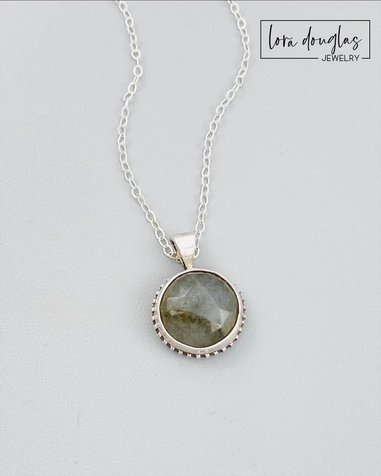 A sterling silver pendant necklace with a faceted labradorite gemstone in the center, attached to an 18-inch chain with a C clasp.