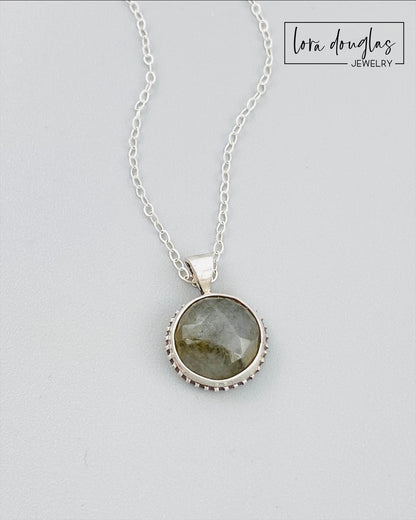 A sterling silver pendant necklace with a faceted labradorite gemstone in the center, attached to an 18-inch chain with a C clasp.