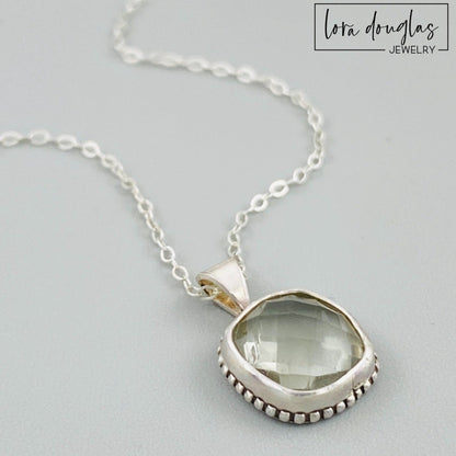 A sterling silver pendant necklace with a faceted green amethyst gemstone, attached to a silver chain.