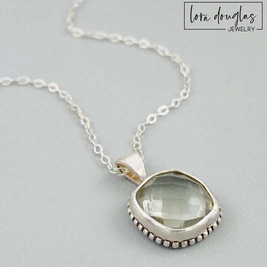 A sterling silver pendant necklace with a faceted green amethyst gemstone, attached to a silver chain.