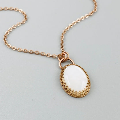 A bronze necklace with a stainless steel chain featuring a round moonstone pendant in a bronze setting.