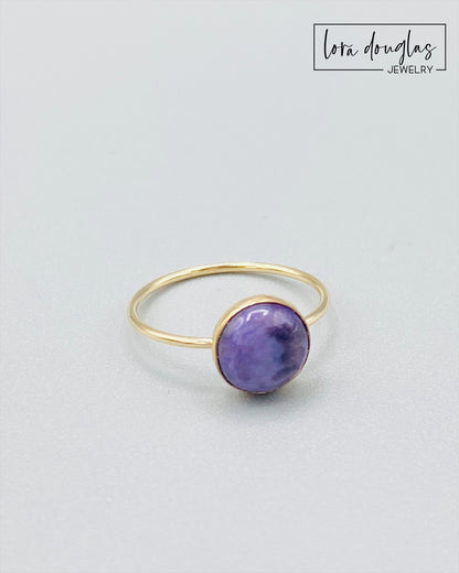 Gold-filled ring with a purple charoite stone set in a gold-filled band, displayed against a white background.