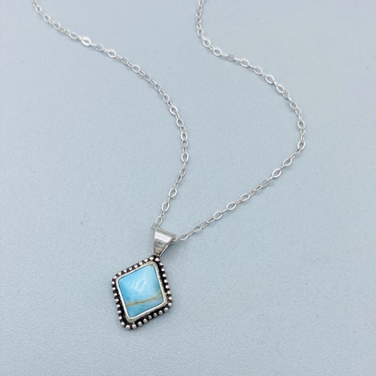 A sterling silver pendant necklace with a turquoise stone and a silver chain.