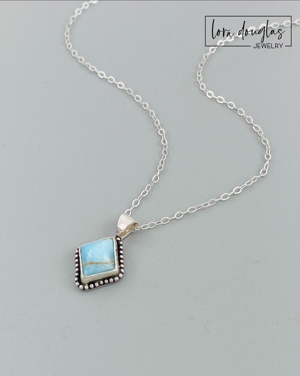 A sterling silver pendant necklace with a turquoise stone and a silver chain.