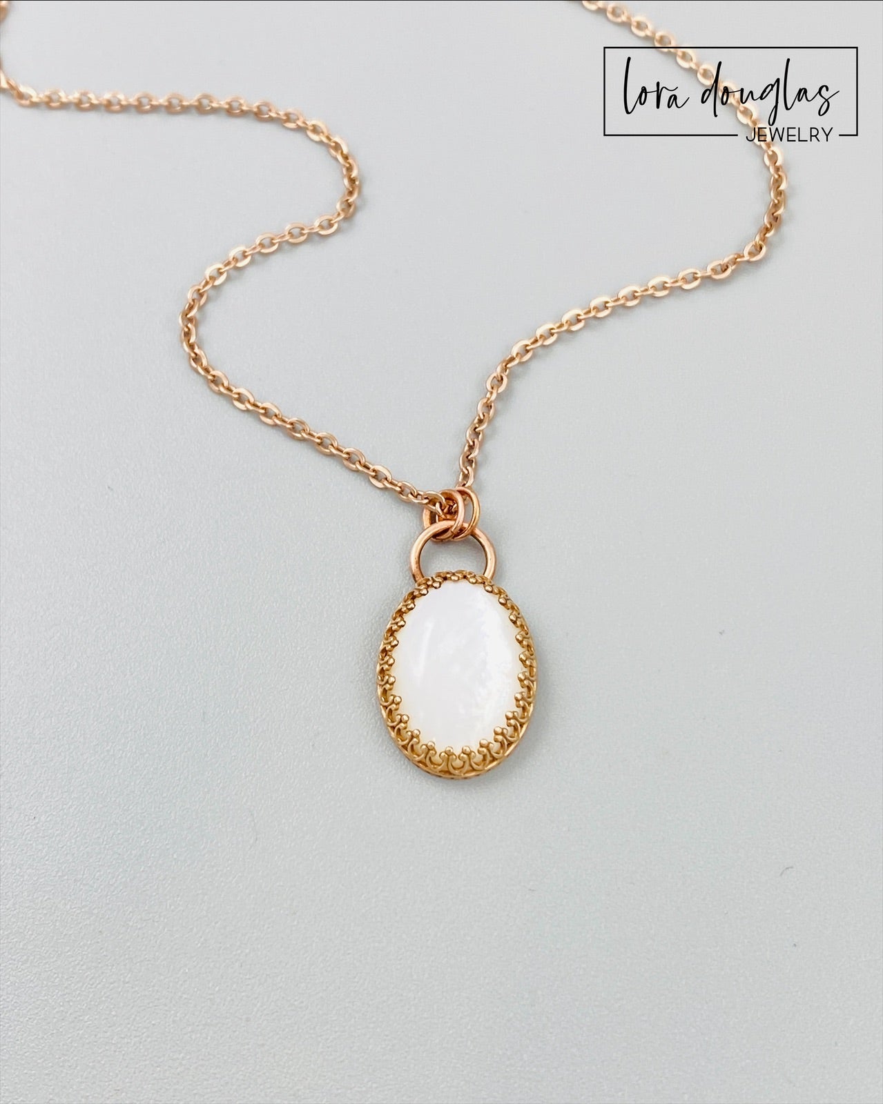 A bronze necklace with a stainless steel chain featuring a round moonstone pendant in a bronze setting.