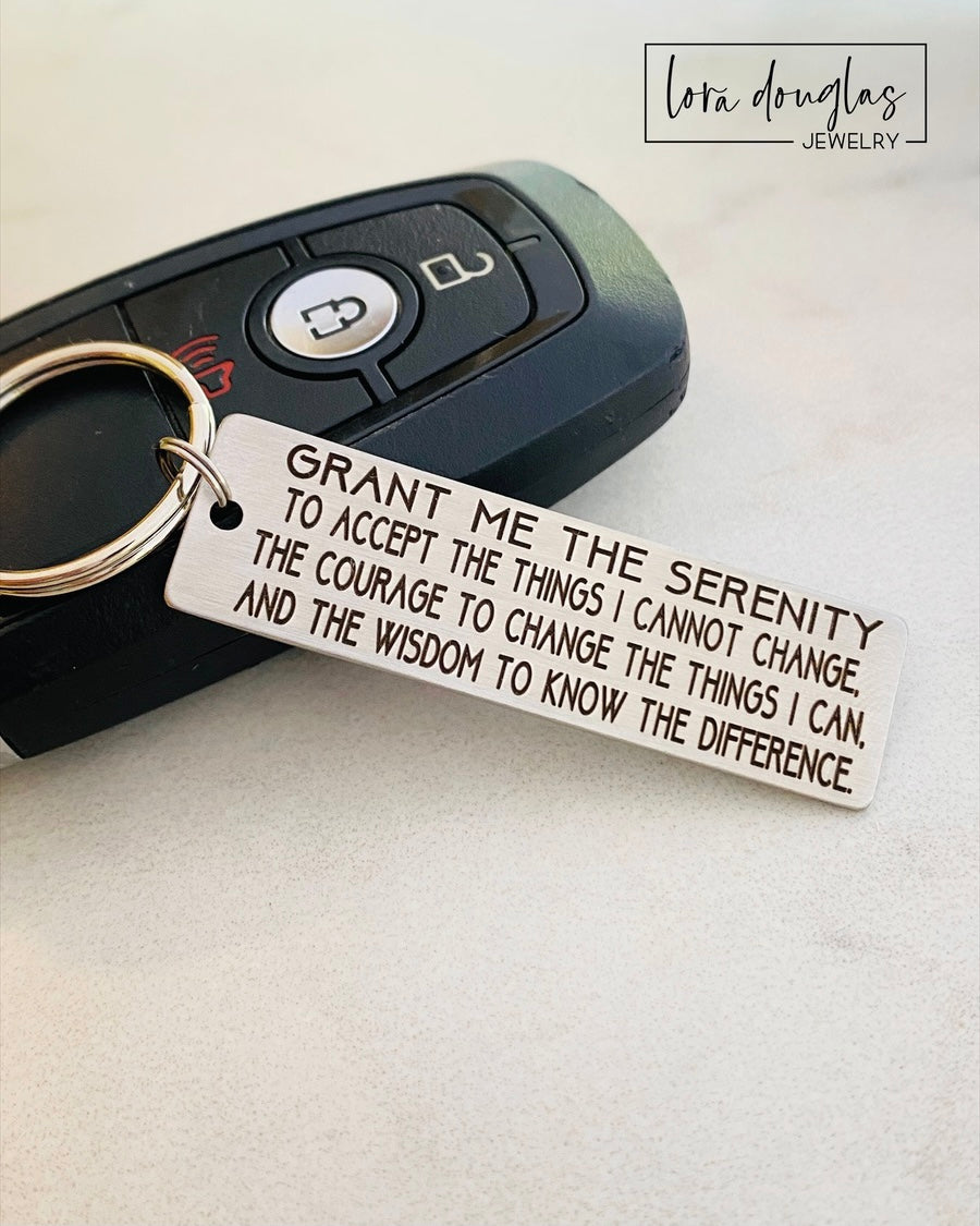Personalized Serenity Prayer keychain crafted from stainless steel with precise laser engraving that will not rub off. Compact engraved plaque measures 2 inches long and attaches securely to keys, making a durable inspirational accessory and meaningful gift for recovery, encouragement, or spiritual reminders.