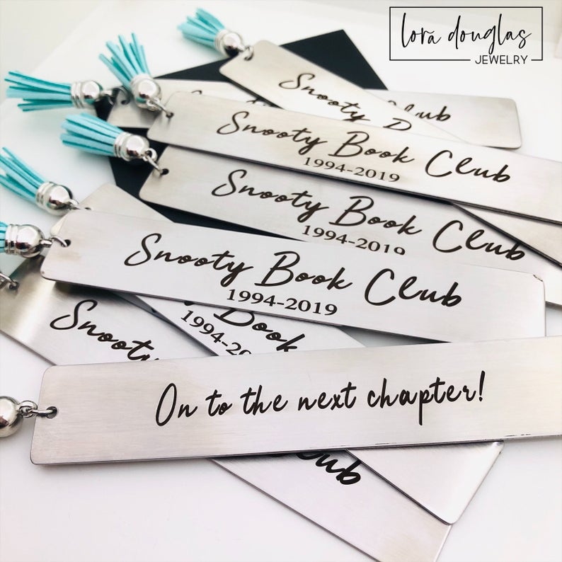 Personalized laser engraved stainless steel bookmark shown as a reading accessory with custom text and tassel detail. Handmade engraved bookmark designed as a thoughtful literary gift, suitable for teacher appreciation, graduation celebrations, or meaningful personalized gifts for readers.