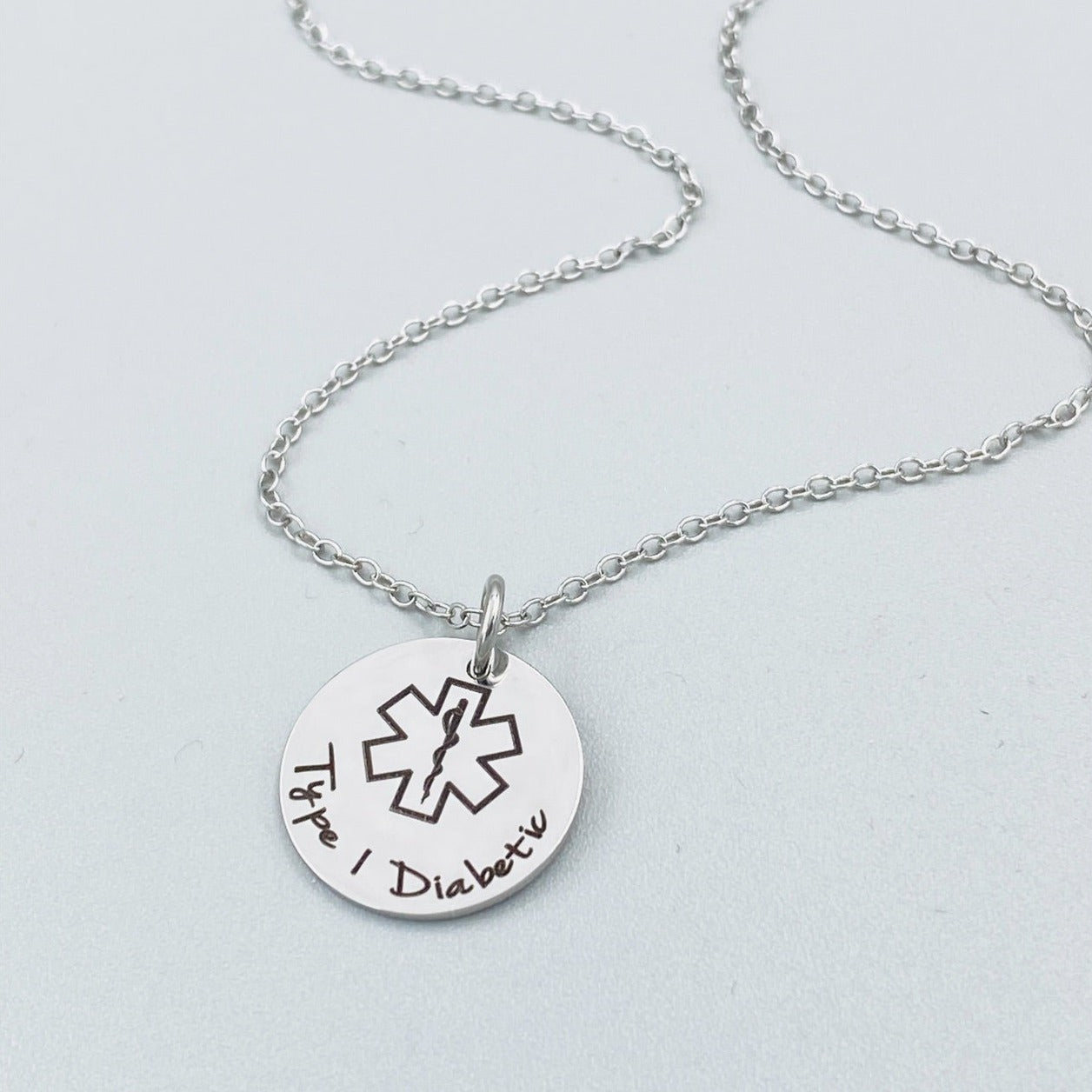 stainless steel personalized medical alert necklace with engraved medical symbol and custom wording shown on delicate chain, minimalist medical ID pendant suitable for allergies diabetes epilepsy and emergency contact details